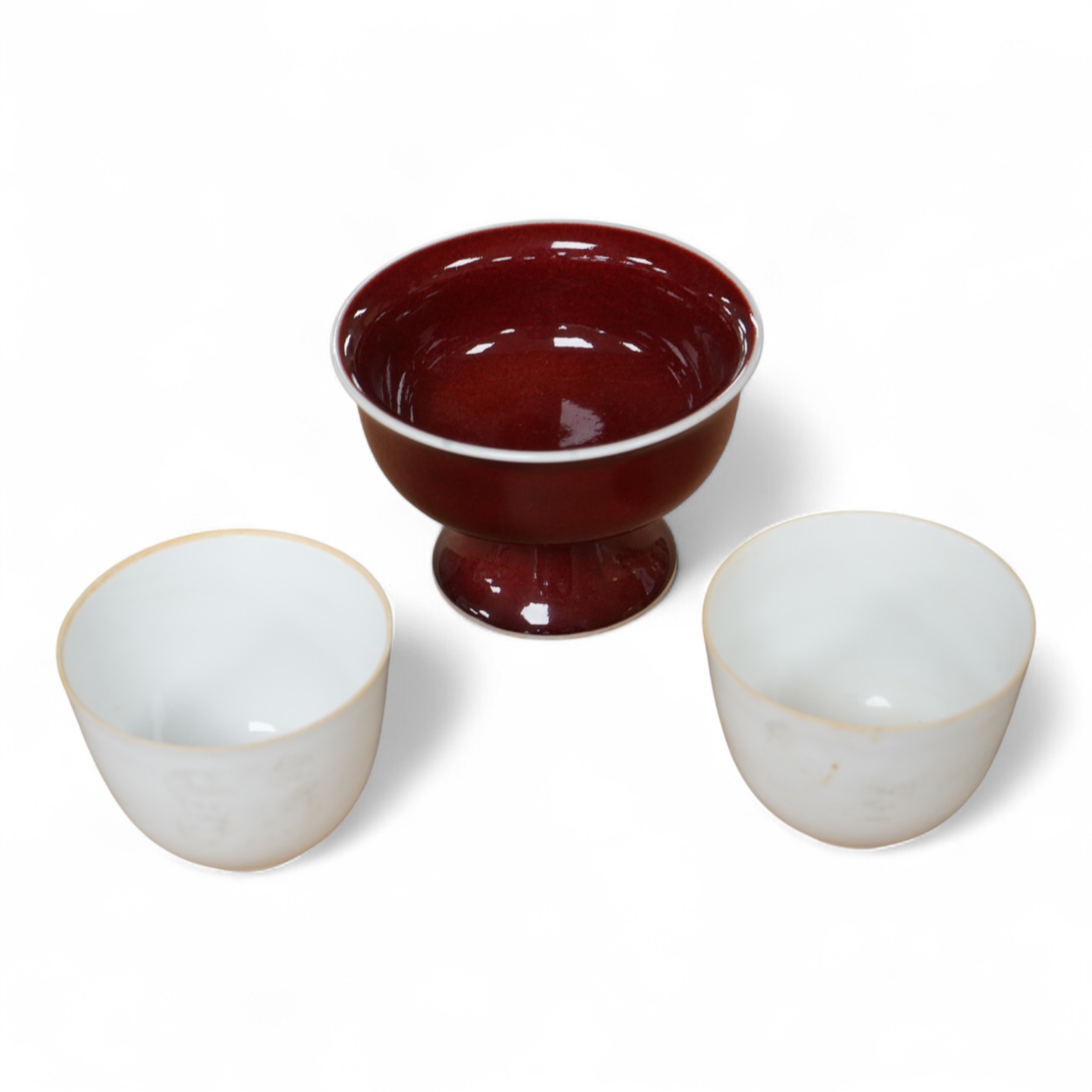 A Chinese red glazed stem cup together with two white glazed tea bowls, tallest 6.5cm